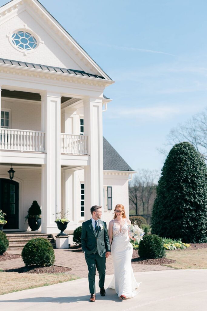 Bride and groom holding hands in front of Donovan Manor.