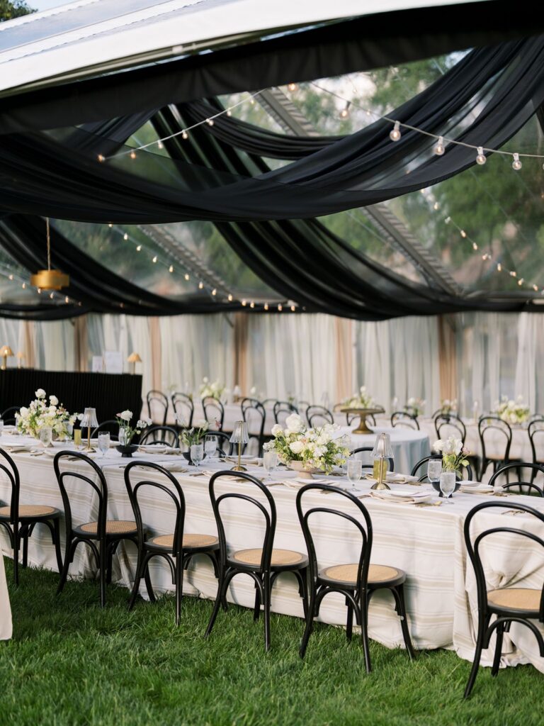 Clear top tent with black ceiling draping and string lights