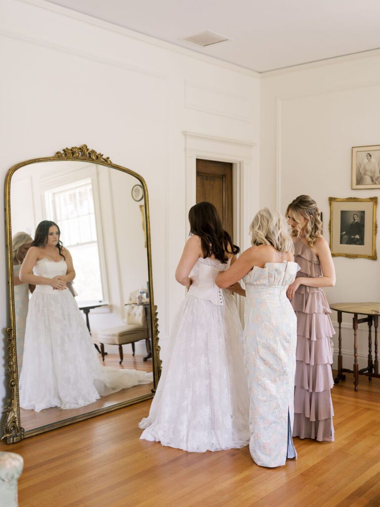 Mom helps bride into her dress 